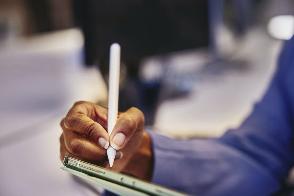 Close up of a hand holding a touch pen and a tablet