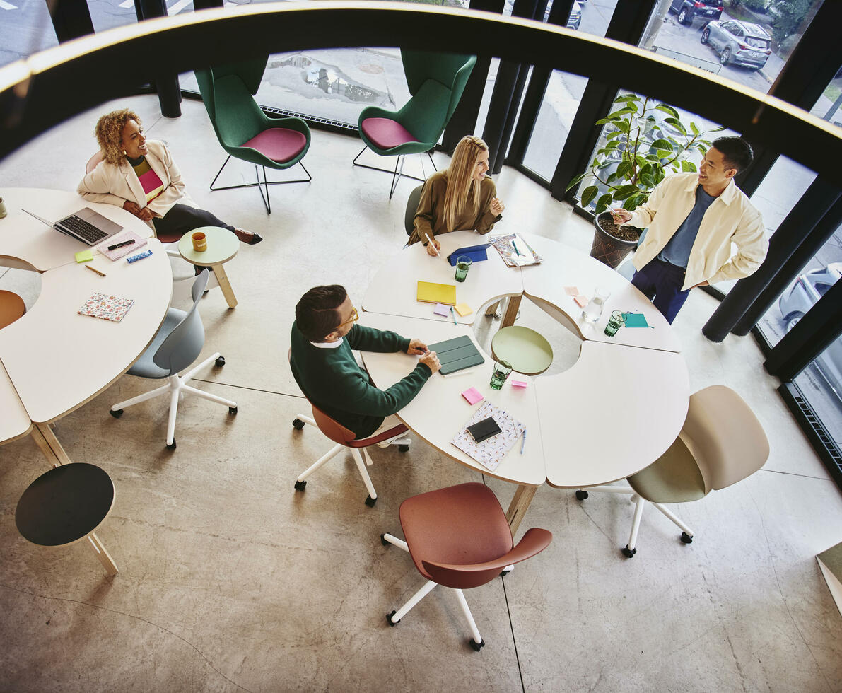 Bird view of people sitting and standing at a round table and having a meeting